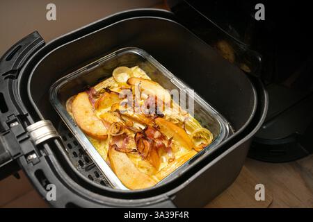 Casserole from chicory, apple, onion and bacon in cheese bechamel sauce in an ovenproof glass dish baked in the black hot air fryer, copy space, selec Stock Photo