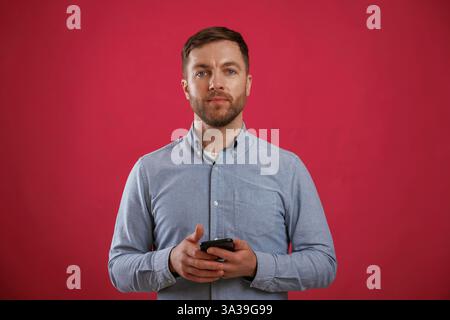 Black smartphone in hands. Man is standing against background in the studio. Stock Photo