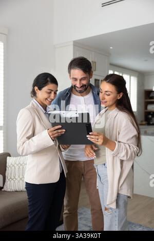 Happy young Indian insurance agent showing agreement to couple Stock Photo