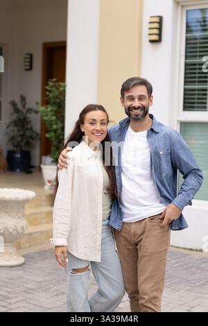 Happy couple of new homeowners posing at entrance Stock Photo