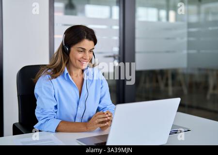 Busy mature woman call center support agent working using laptop in office. Stock Photo