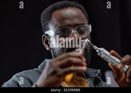 Focused individual examining lab equipment while wearing protective glasses Maintaining precision in laboratory setting ensuring accuracy in procedures Stock Photo