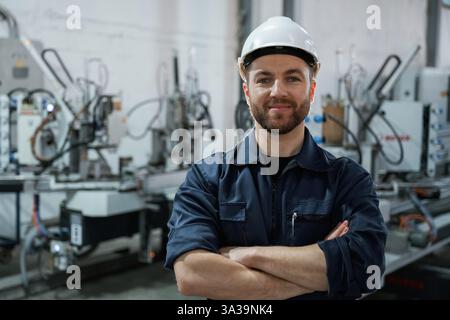 Front view. Factory worker is indoors with hard hat. Stock Photo