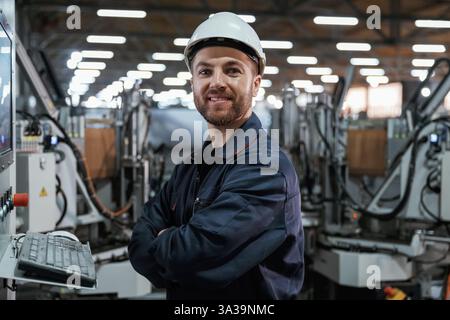 Using equipment, operator. Factory worker is indoors with hard hat. Stock Photo