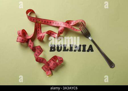 Word Bulimia, measuring tape and fork on olive background, top view Stock Photo