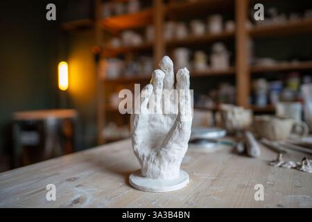 Pottery workshop with clay hand palm on table, bespoke piece of modern art an unusual ceramic stand Stock Photo