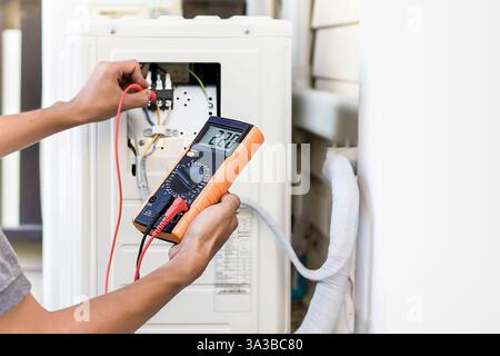Air conditioner repairman using electricity meter to check air conditioner operation, maintenance concept Stock Photo