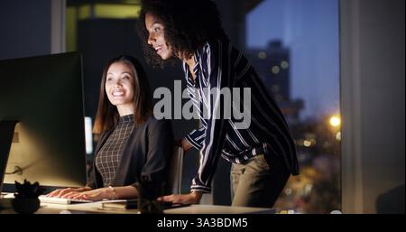 Business women, night and computer with web design for company deadline, project or teamwork at office. Female people, employees or designers working Stock Photo