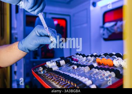 Close-up of paramedic hands holding ampoule with medication in ambulance car of emergency medical service. Stock Photo