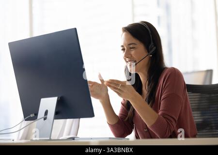 Positive Latin businesswoman in headphones talking on video call Stock Photo