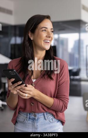 Happy Hispanic business professional woman in casual using smartphone Stock Photo