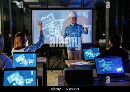 Male architect is showing construction site project on blue projector for people. Stock Photo