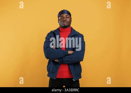 Serious facial expression. Handsome black man is in the studio against yellow background. Stock Photo