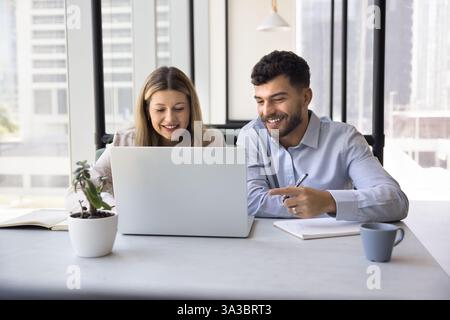 In open-space office two teammates working on joint online project Stock Photo