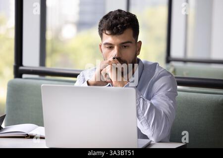 Man deeply focused on his work, staring at laptop screen Stock Photo