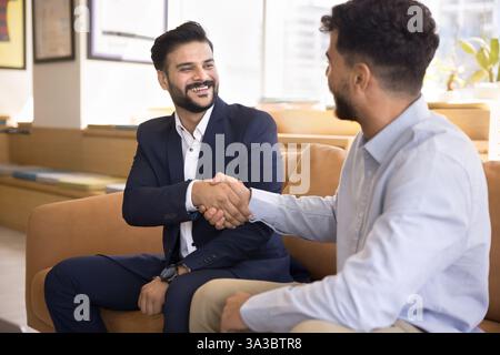 Two millennial 30s businessmen shaking hands, conclude successful meeting Stock Photo