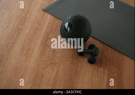 Fitness ball and dumbbells on the floor with yoga mat. Stock Photo