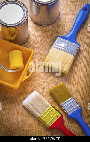 Tray roller paint brushes cans on wooden board Stock Photo