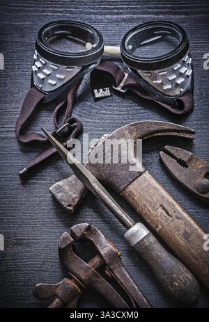 Vertical view goggles hammer pliers rasp on vintage wood board Stock Photo