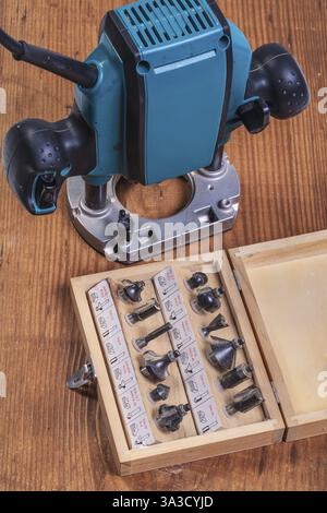 Woodworking tools â€“ set of roundover router bits in box and plunge pouter on old wooden board Stock Photo