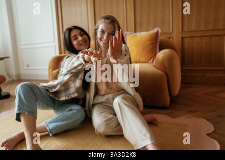 Having fun, sitting. Two happy young female best friends are indoors. Stock Photo