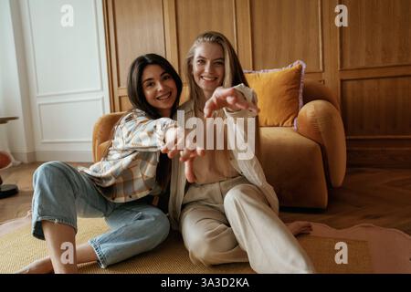 Having fun, sitting. Two happy young female best friends are indoors. Stock Photo