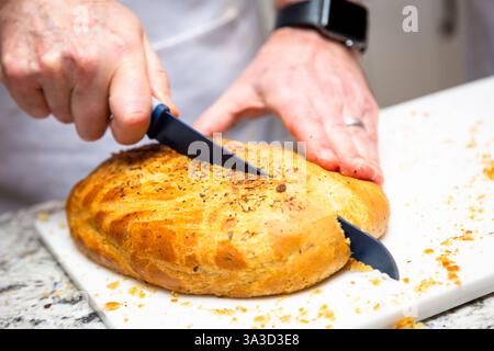 Home made Spanish bread being cut with a knife Stock Photo