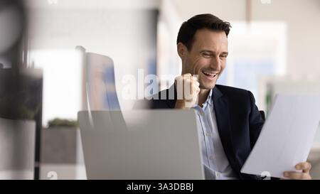 Cheerful excited Hispanic executive man examining legal financial document Stock Photo