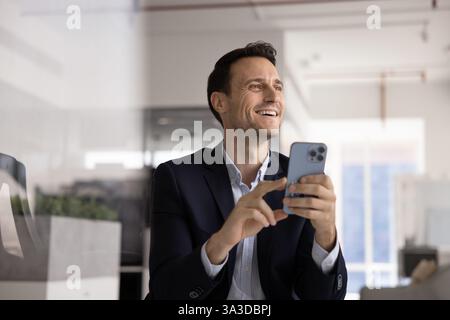 Cheerful successful Hispanic executive man typing on smartphone Stock Photo
