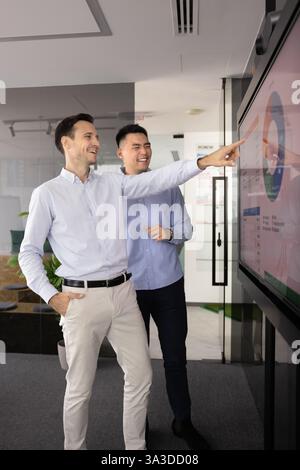 Cheerful male business colleagues discussing product benchmarks Stock Photo