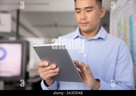 Focused young Asian business professional man using Internet technology Stock Photo