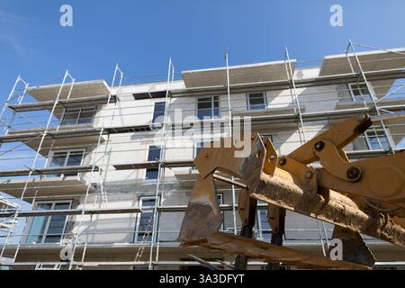 A bustling construction site featuring scaffolding, heavy machinery, and various activities Stock Photo