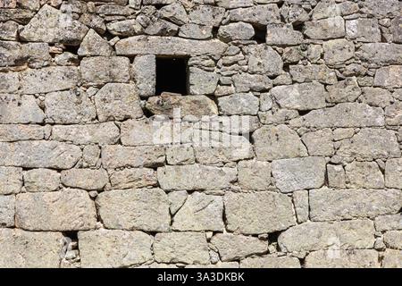 Detail of Side of an old abandoned granite detached house with a open window. Stock Photo