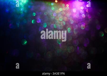 A photograph of an abstract glittery background with colourful light against a black background Stock Photo