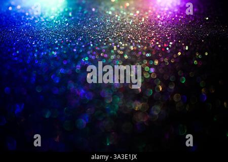 A photograph of an abstract glittery background with colourful light against a black background Stock Photo