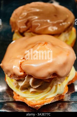 Rich Cream-Filled Eclairs with Chocolate and Caramel Glaze - Gourmet Pastries for Dessert Lovers - Indulge in Decadent Baked Treats - Perfect for Celebrations and Sweet Cravings Stock Photo