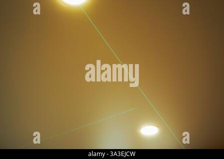 The bright green laser level lines guide you to measure and level the ceiling in an unfinished building. Stock Photo