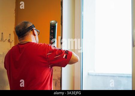 The worker - master foams the window with mounting foam, close-up. Stock Photo