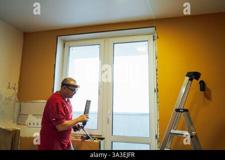 Process installation of window slopes. Using mounting foam. On a peach background. Stock Photo