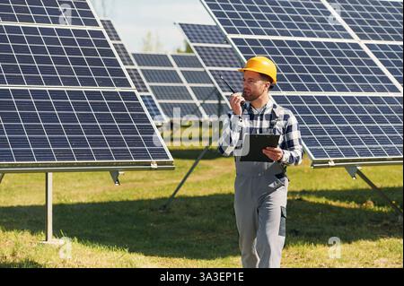 Communication by using walkie talkie. Engineer with photovoltaic solar panels outdoors at daytime. Stock Photo