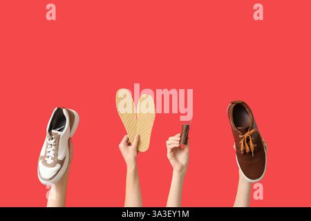 Female hands with shoes, insoles and sewing thread on red background. Shoe repair concept Stock Photo