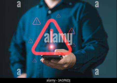 Man using smartphone with warning sign.Notification error and virus detection spyware. Emergency warning alert alarm on smartphone. Data network prote Stock Photo
