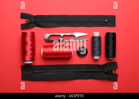 Different sewing supplies on red background, flat lay Stock Photo