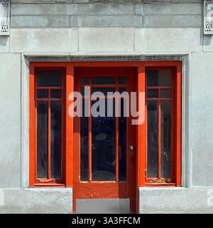 A striking red wooden door with glass panels set within a light stone facade in Chicago Stock Photo