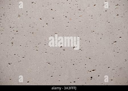 Rough mottled concrete surface shows a pattern of small dark spots and pores that create a unique textured gray wall Stock Photo