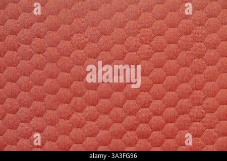 Detailed view of a coral colored fabric texture featuring a repeating hexagon pattern; creates a tactile and visually appealing surface Stock Photo