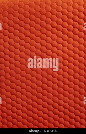 A close up of vibrant orange colored geometric fabric pattern The pattern is uniformly textured with repeating hexagons Stock Photo