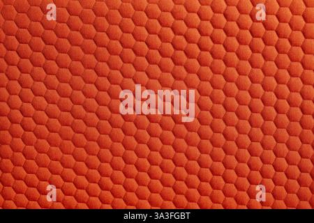 Close up of a vibrant orange fabric featuring a textured honeycomb pattern creating a visually appealing and tactile surface Stock Photo