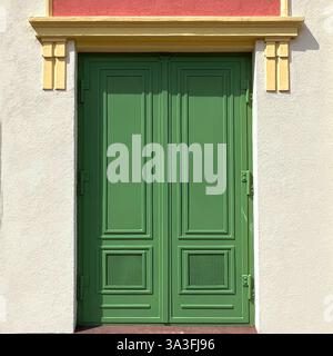 Green double door with intricate paneling, framed by a pastel-colored facade, located in Warsaw, Poland. Stock Photo