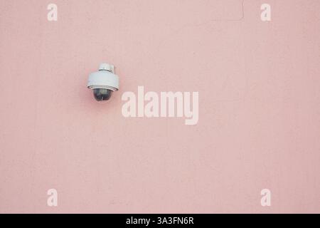 Security camera mounted on pink wall enhances safety in location Stock Photo